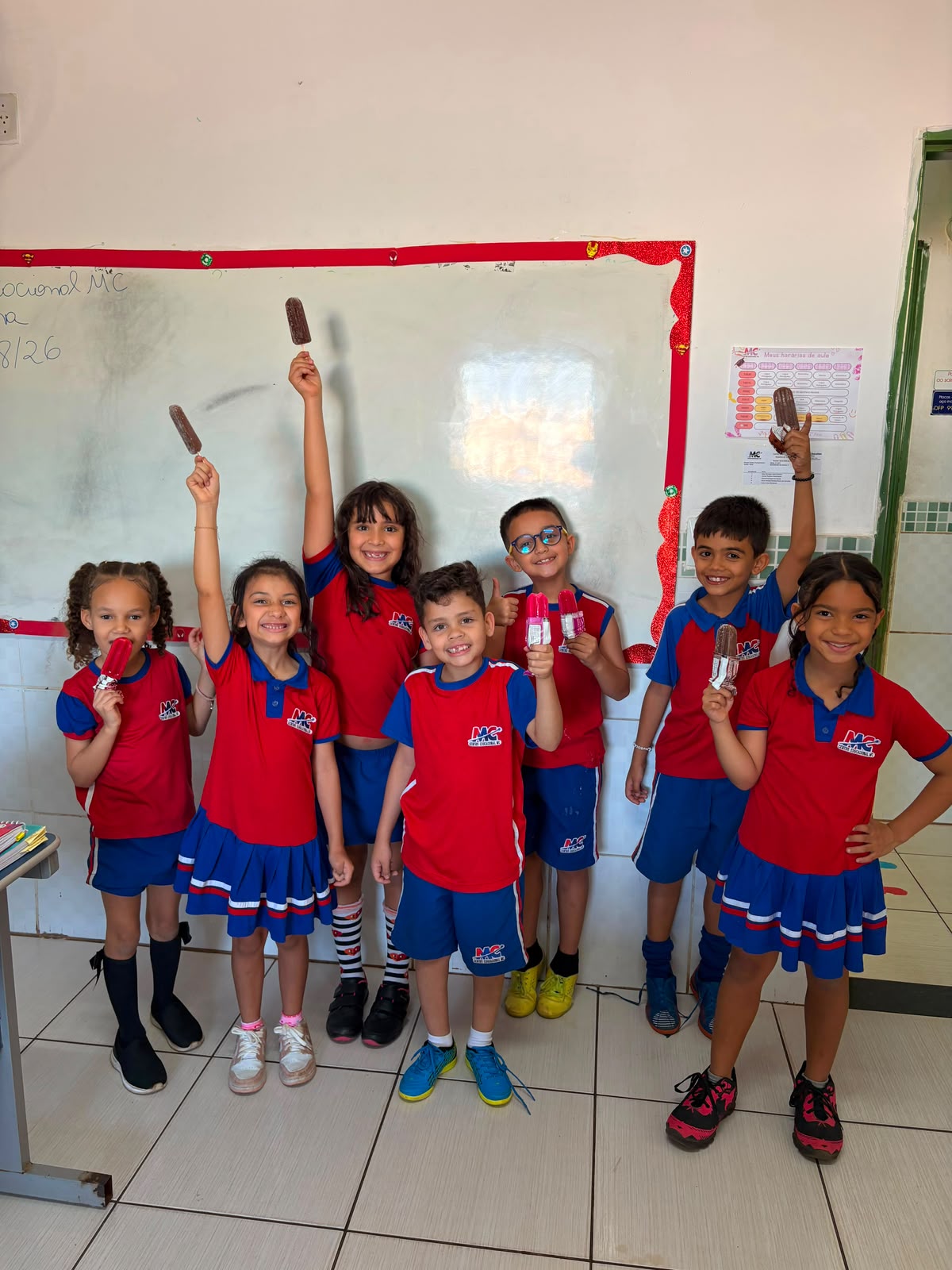 Alunos sorrindo com picolés na sala de aula
