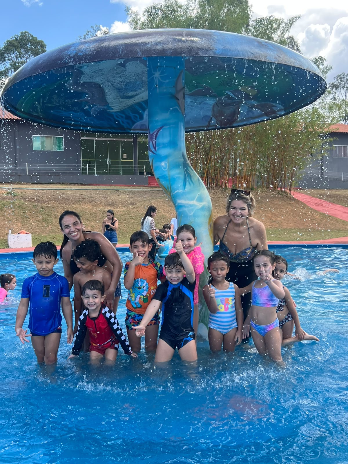 Crianças e professoras se divertindo na piscina durante atividade recreativa